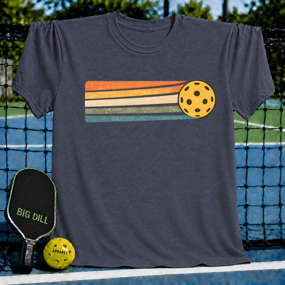 Periwinkle blue unisex t-shirt featuring a yellow pickleball and retro orange, cream, and teal sunset stripes.