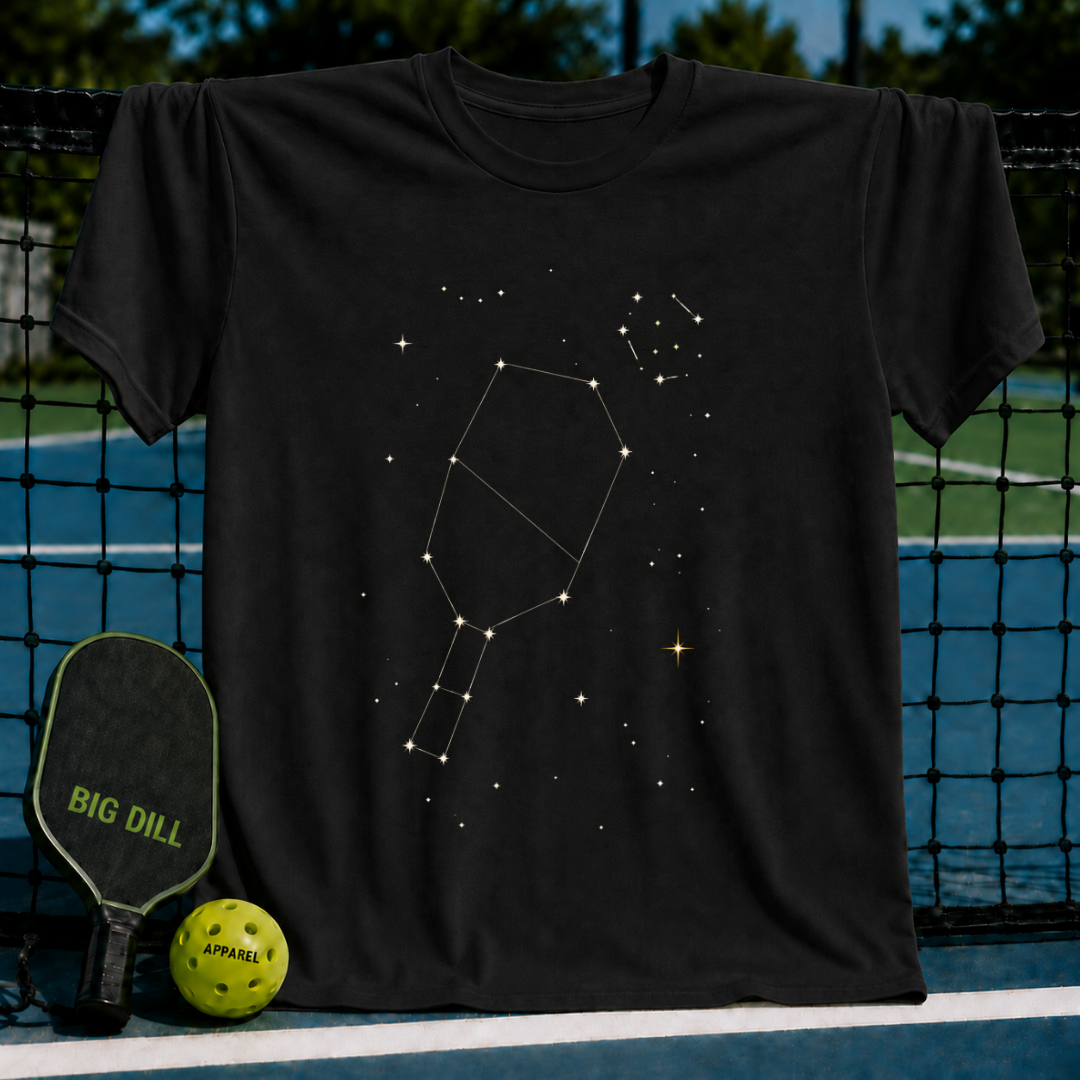 Black cotton t-shirt featuring a white pickleball paddle constellation design against a starry night sky graphic.