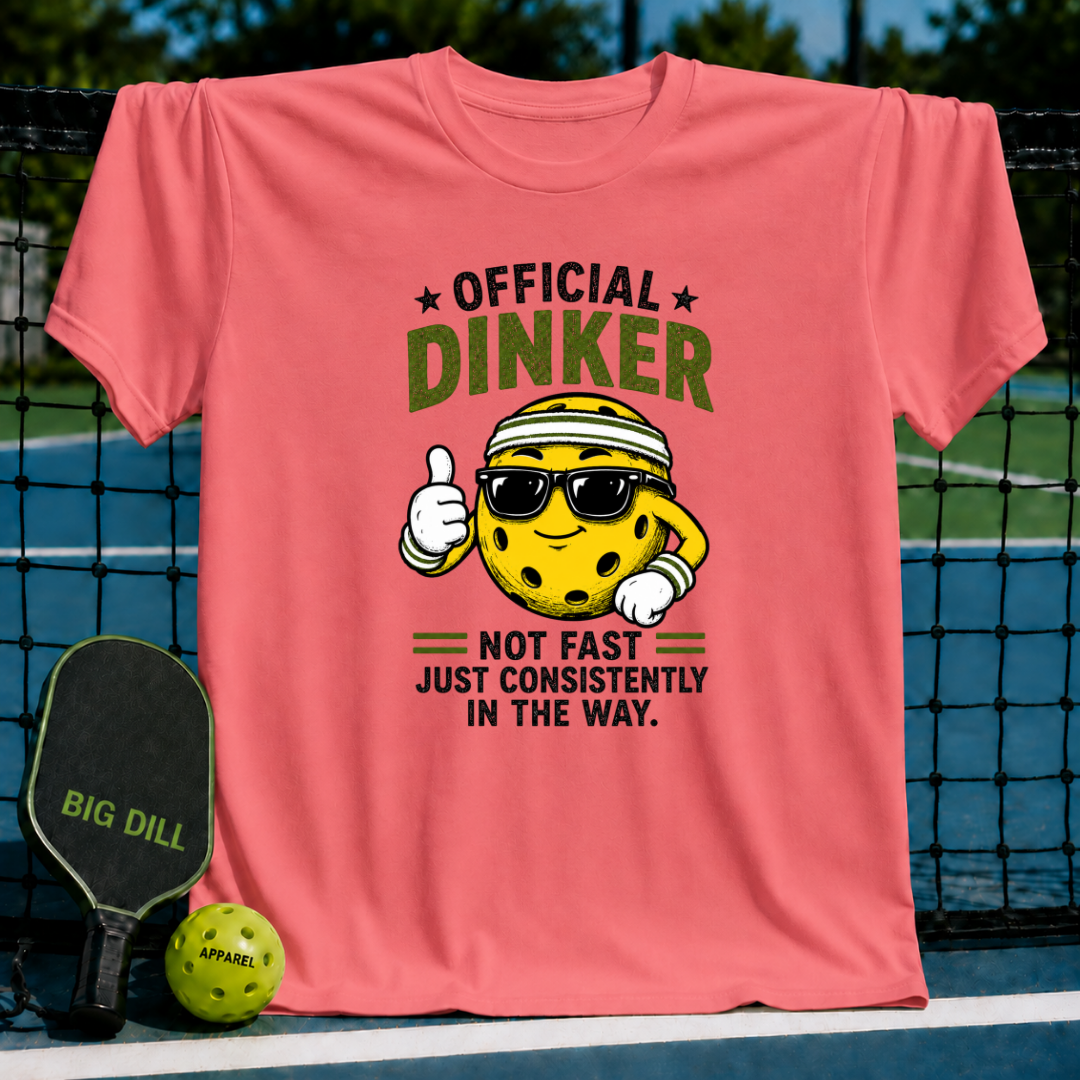 Coral pink crewneck t-shirt featuring a cartoon pickleball character with sunglasses and the text Official Dinker.