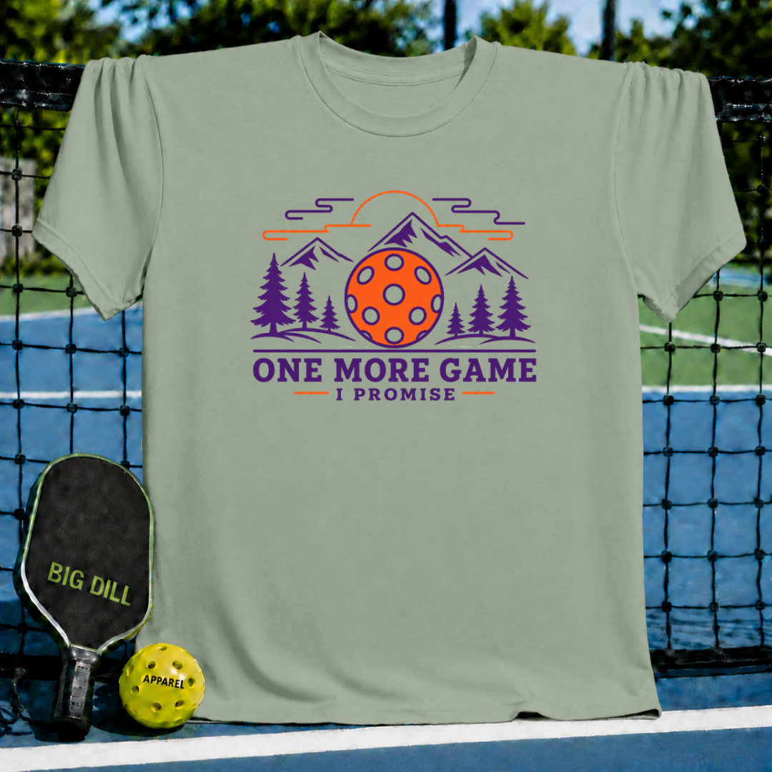Sage green crewneck t-shirt featuring a mountain, pine tree, and pickleball graphic with the text One More Game I Promise.