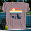 Mauve crewneck t-shirt featuring a retro sunset, pickleball court, paddle, ball, and cat silhouette graphic.