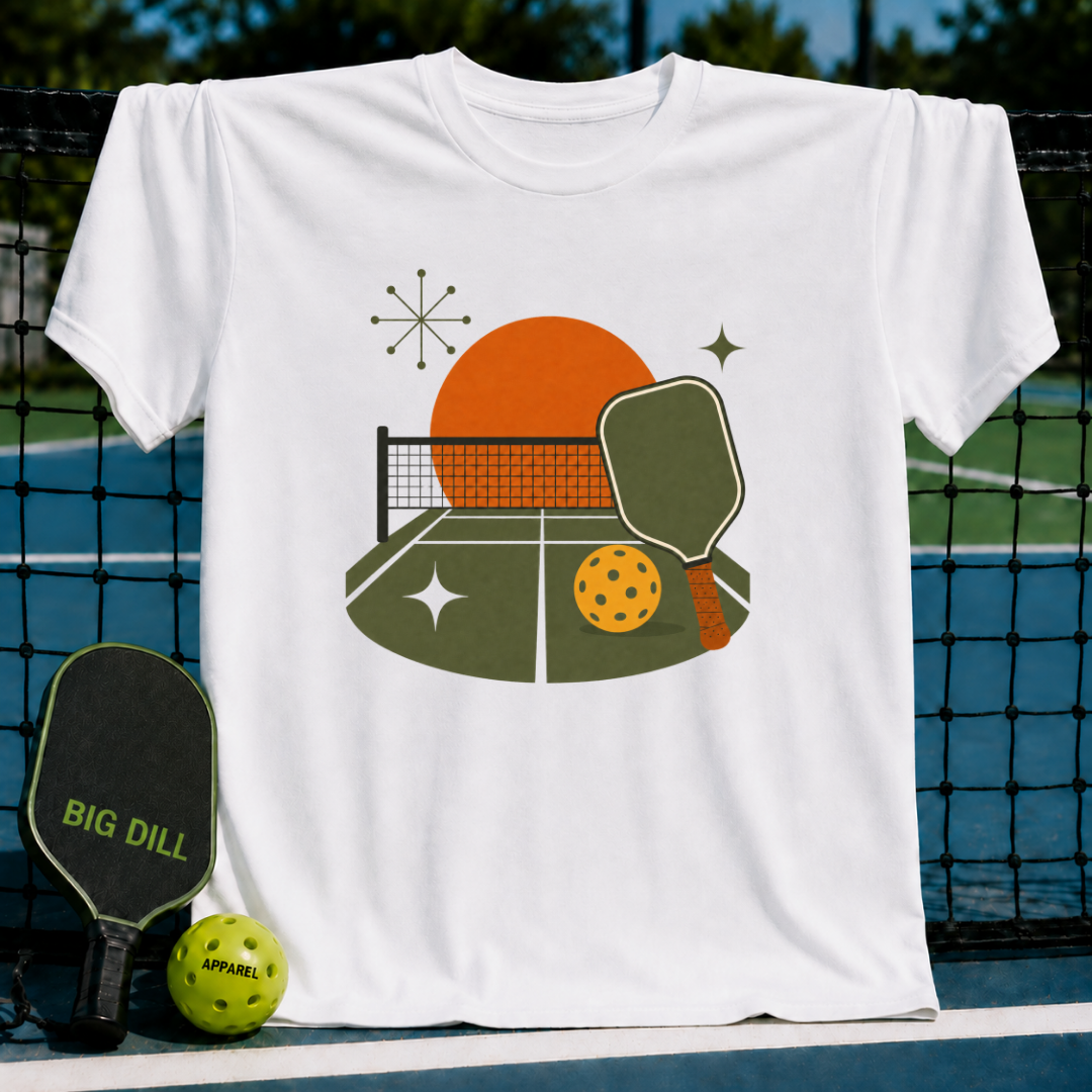 White cotton t-shirt featuring a midcentury modern pickleball court graphic with an orange sun and retro star accents.