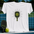 White crew neck t-shirt featuring a green pickleball paddle graphic with sunburst lines on a pickleball court background.