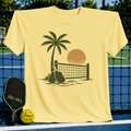 Butter yellow unisex t-shirt featuring a brown retro palm tree, pickleball net, and paddle silhouette graphic.
