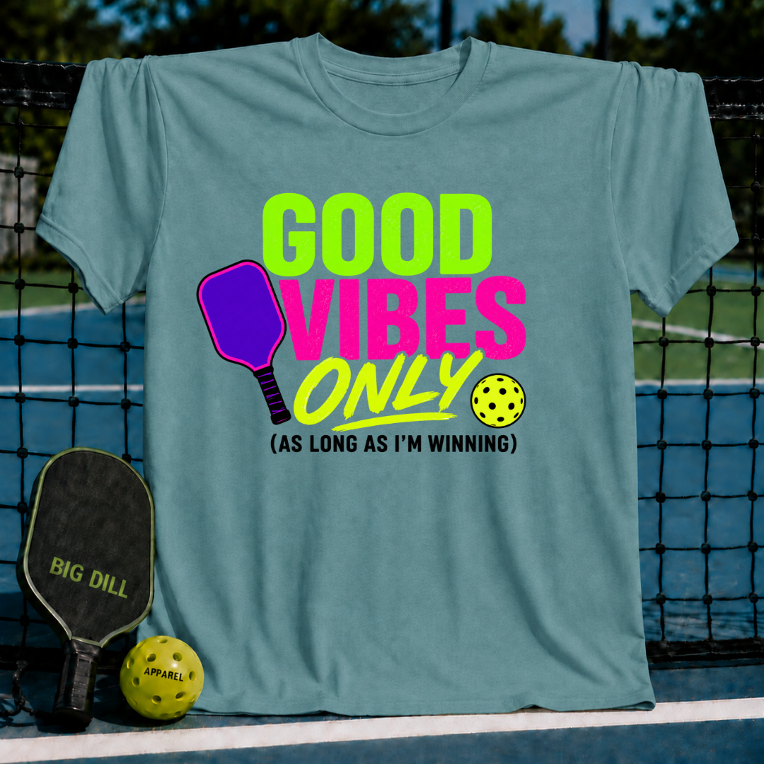 Periwinkle unisex t-shirt featuring a neon pink and green pickleball graphic with the text Good Vibes Only As Long As I'm Winning.