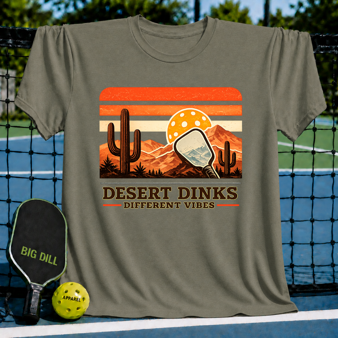 Olive green crewneck t-shirt featuring a retro desert sunset graphic with a pickleball paddle, cacti, and Desert Dinks text.