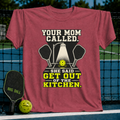 Crimson red unisex t-shirt featuring a pickleball graphic with crossed paddles, a spotlighted ball, and bold typography.