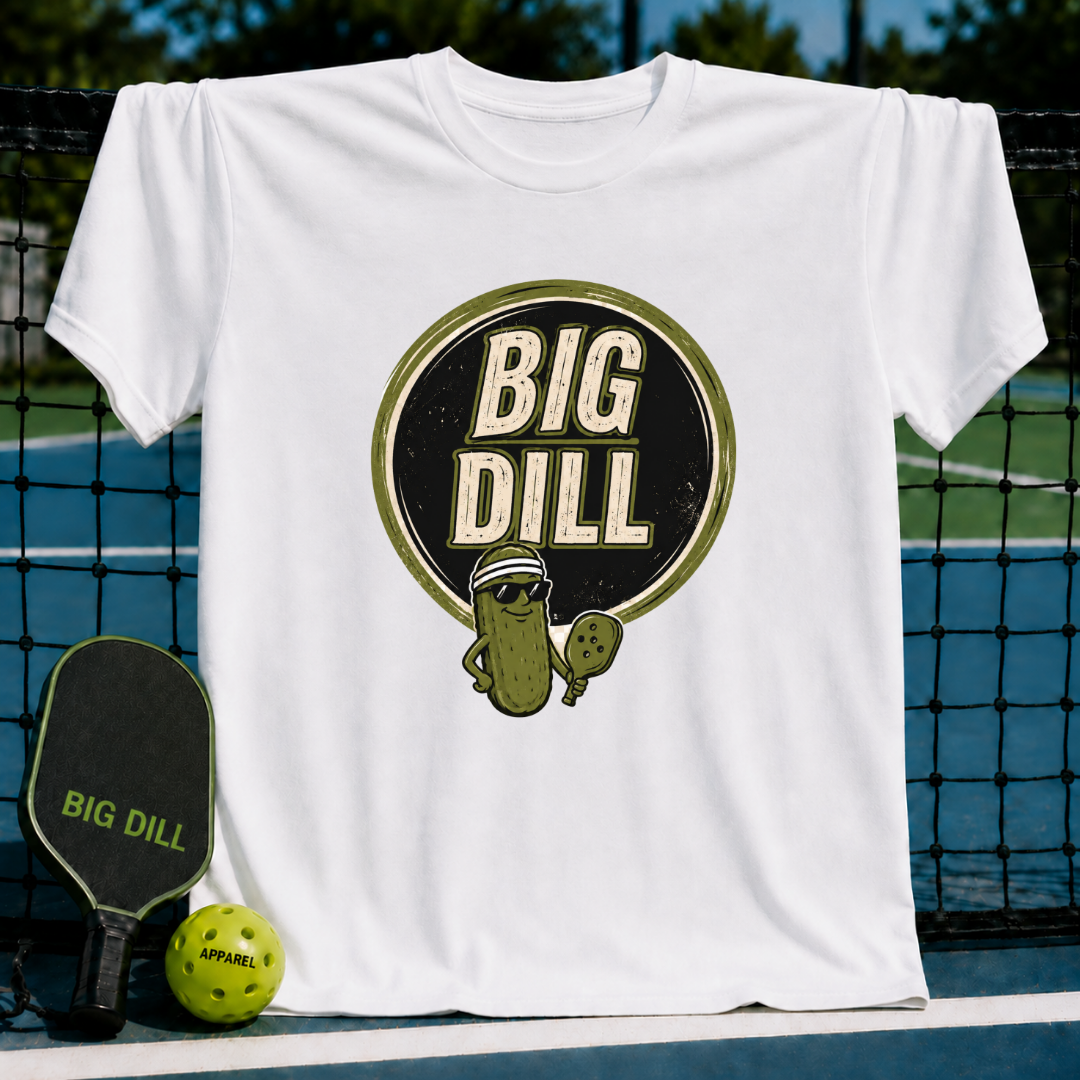 White crew neck t-shirt featuring a Big Dill pickle graphic with sunglasses and a pickleball paddle on a court background.