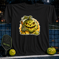 Black unisex t-shirt featuring a flaming jack-o'-lantern pickleball graphic with a paddle and ball on a court background.