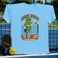 Light blue pickleball t-shirt featuring a cartoon pickle character, net graphic, and Sorry About The Net Cord text.