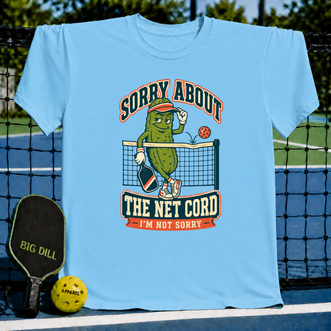 Light blue pickleball t-shirt featuring a cartoon pickle character, net graphic, and Sorry About The Net Cord text.