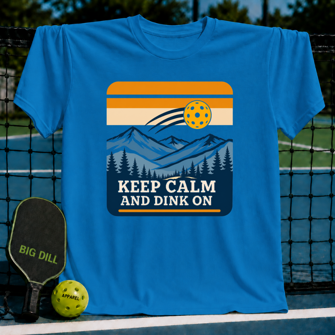 Bright blue crewneck t-shirt featuring a retro mountain and pickleball graphic with the text Keep Calm And Dink On.