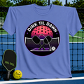 Periwinkle blue unisex t-shirt featuring a retro synthwave pickleball graphic with crossed paddles and a neon moon.