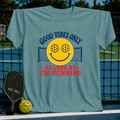 Teal unisex t-shirt featuring a retro smiley face with pickleball eyes, a net, and the text Good Vibes Only As Long As I'm Winning.