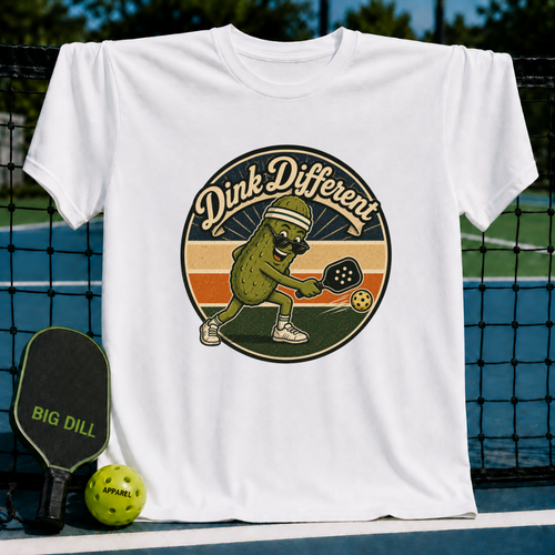White unisex t-shirt featuring a retro pickleball-playing pickle graphic with the text Dink Different on a pickleball court.