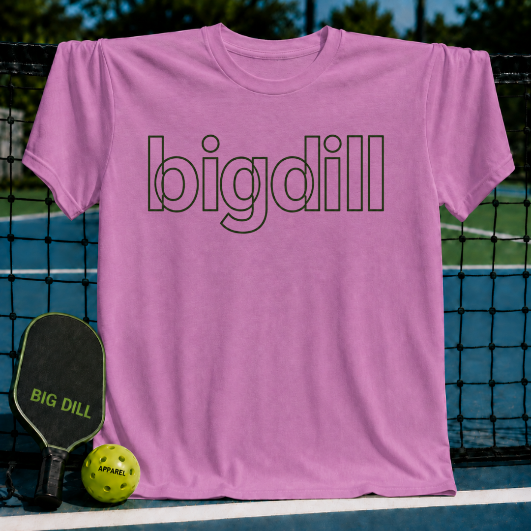 Pink unisex t-shirt featuring a bold, black outline Big Dill wordmark, displayed on a pickleball court net.