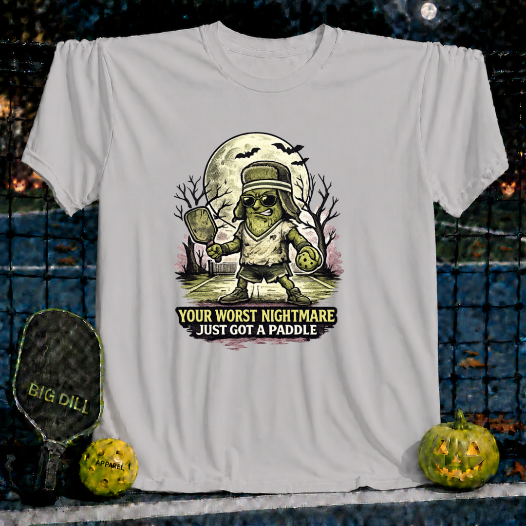 Light grey unisex t-shirt featuring a spooky pickleball-playing monster graphic with the text Your Worst Nightmare Just Got A Paddle.