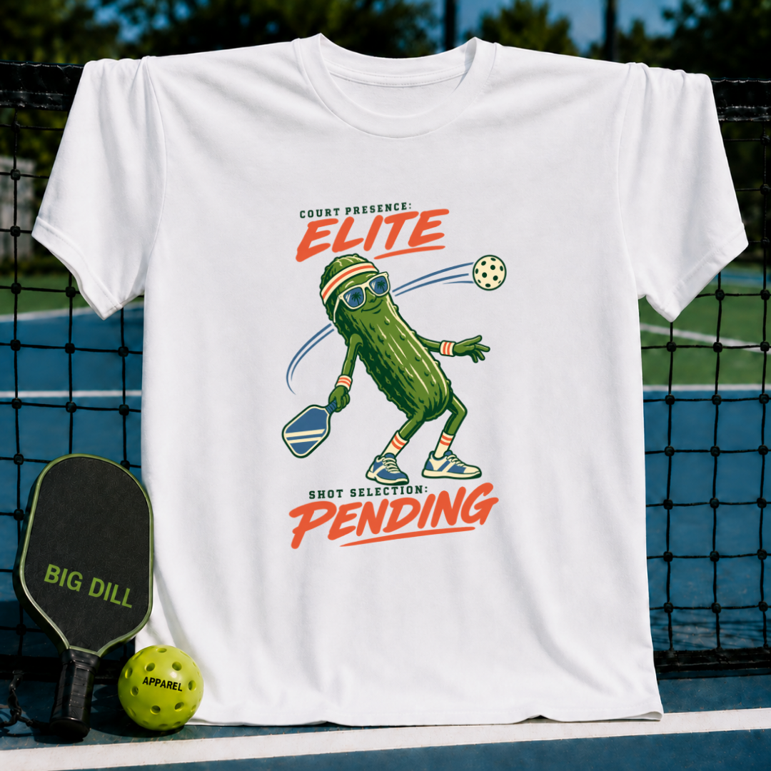 White crew neck t-shirt featuring a cartoon pickle playing pickleball with the text Court Presence Elite Shot Selection Pending.