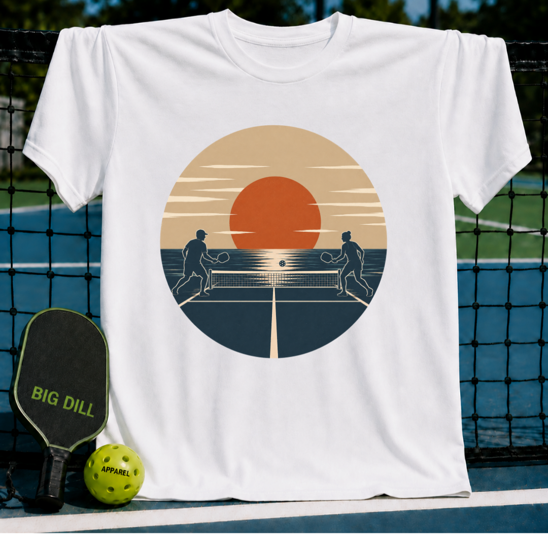 White unisex t-shirt featuring a retro sunset pickleball graphic with two silhouettes playing on a court.
