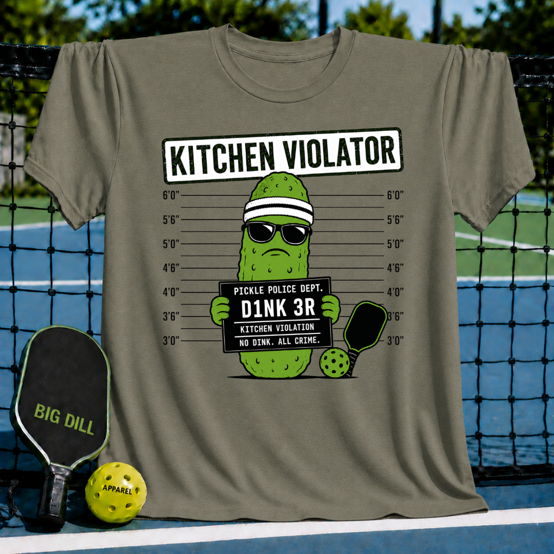 Olive green t-shirt featuring a pickle mug shot graphic with sunglasses, a headband, and a pickleball paddle on a court.
