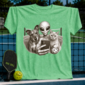 Heather green unisex t-shirt featuring a vintage-style illustration of an alien, dog, and cat taking a pickleball selfie.