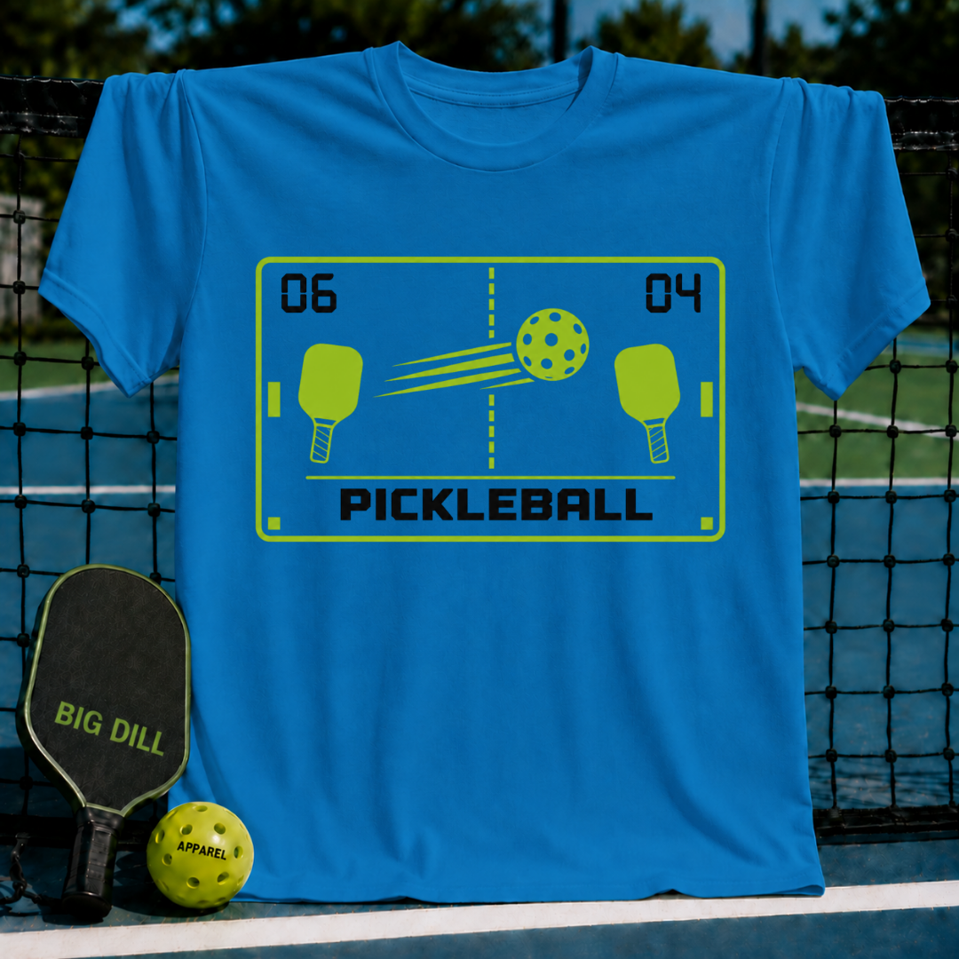 Bright blue unisex t-shirt featuring a retro arcade-style pickleball graphic in neon green on a pickleball court background.