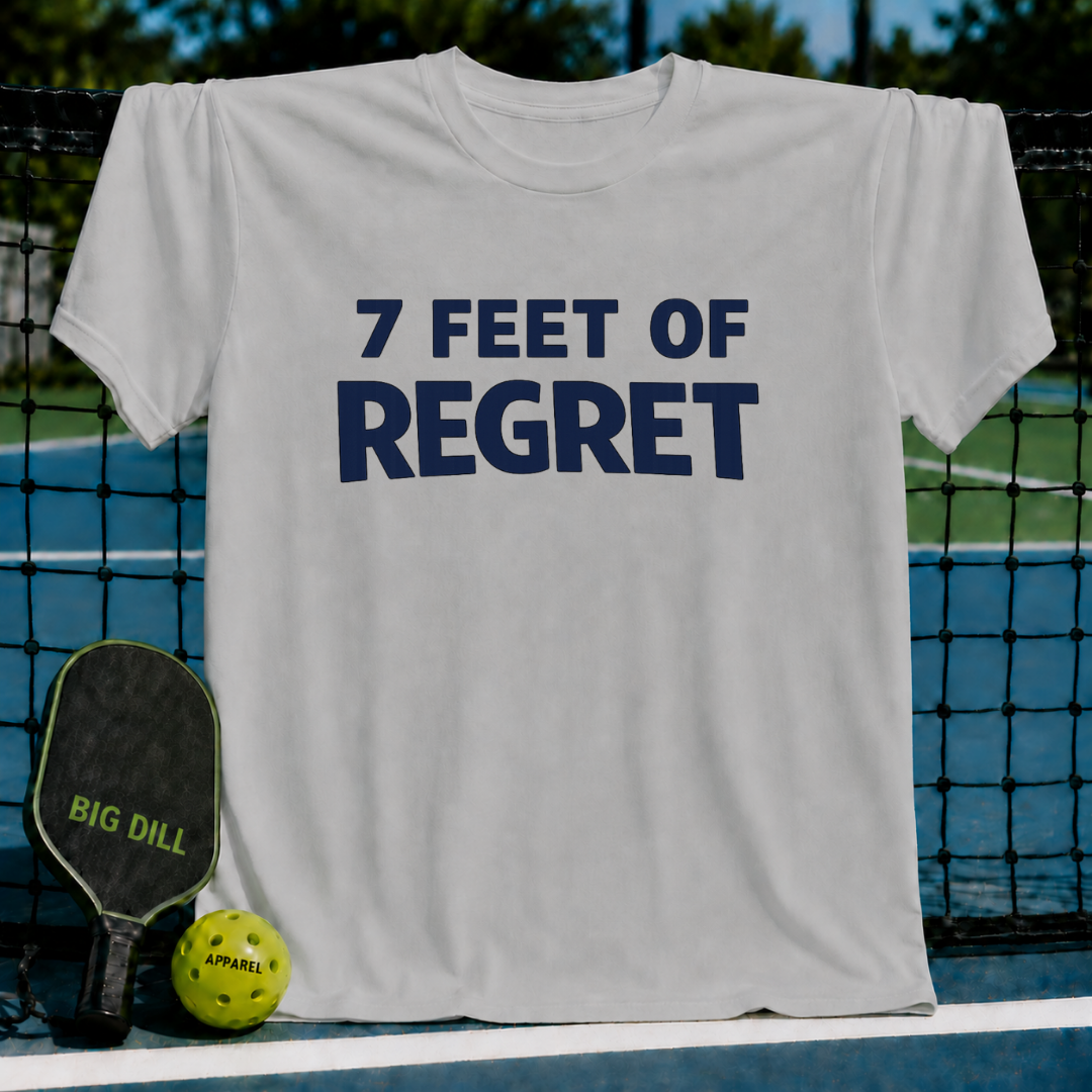 Light gray unisex t-shirt featuring bold navy text reading 7 FEET OF REGRET, displayed on a pickleball court net.