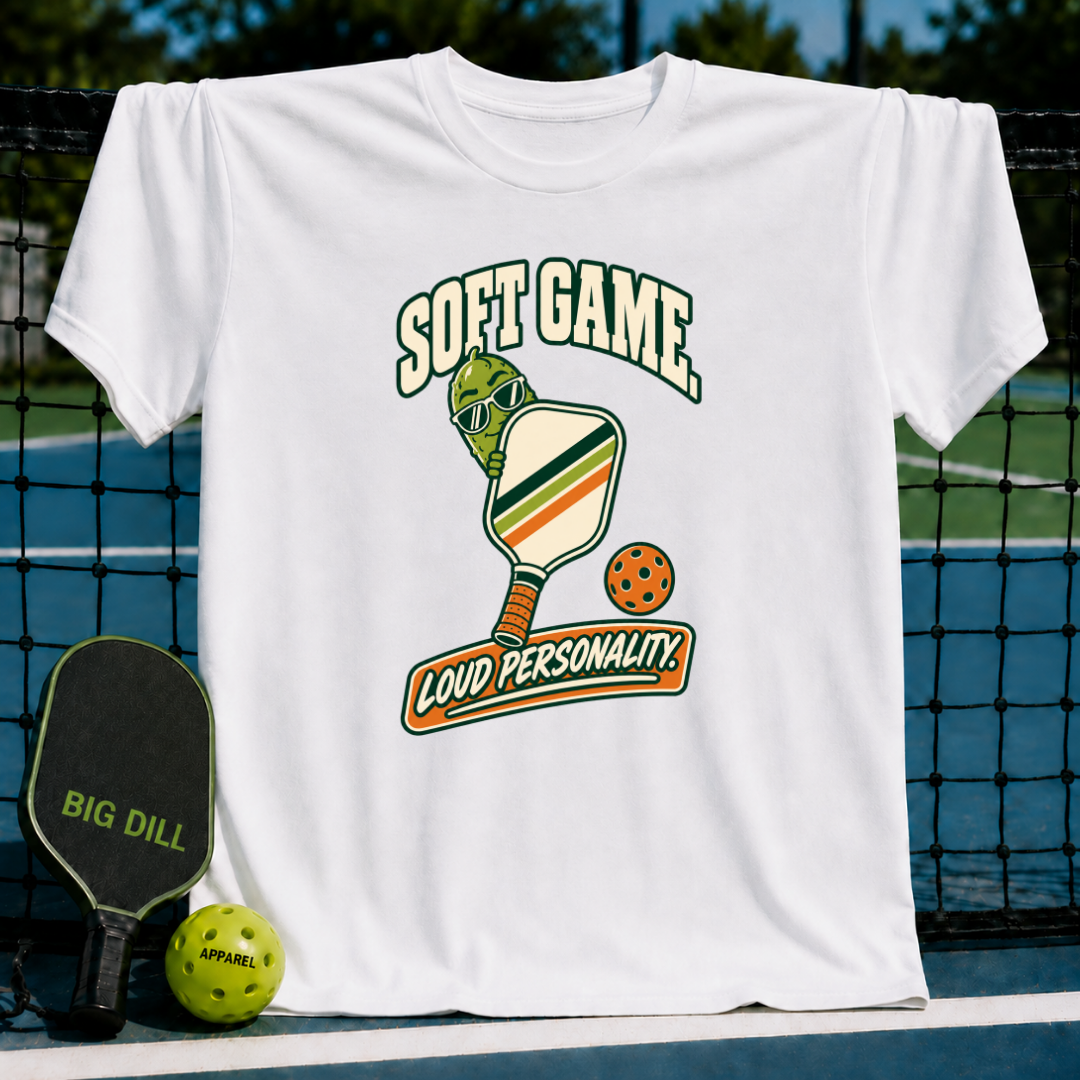 White cotton t-shirt featuring a pickleball-themed graphic with a pickle character and the text Soft Game, Loud Personality.