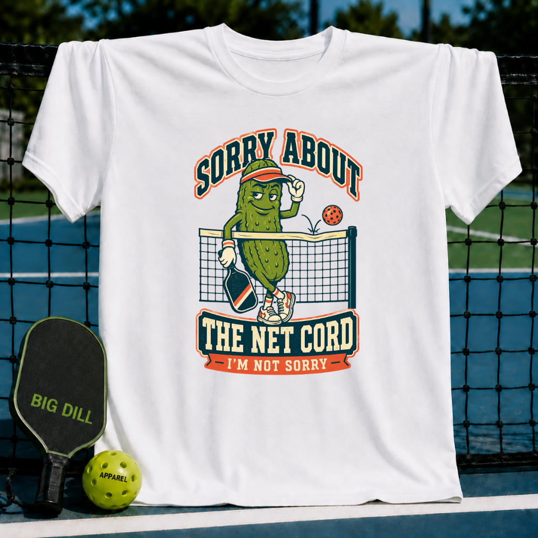 White crew neck t-shirt featuring a cartoon pickle playing pickleball with the text Sorry About The Net Cord.