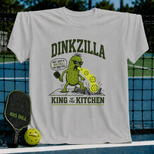 Light gray unisex t-shirt featuring a Dinkzilla pickleball graphic with a green monster, paddle, and balls on a court.
