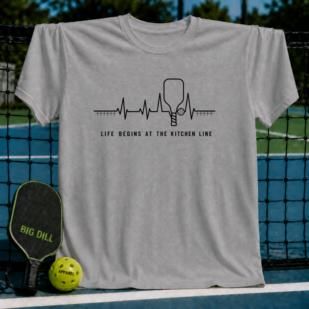Light gray unisex t-shirt featuring a black heartbeat graphic with a pickleball paddle and text on a pickleball court.