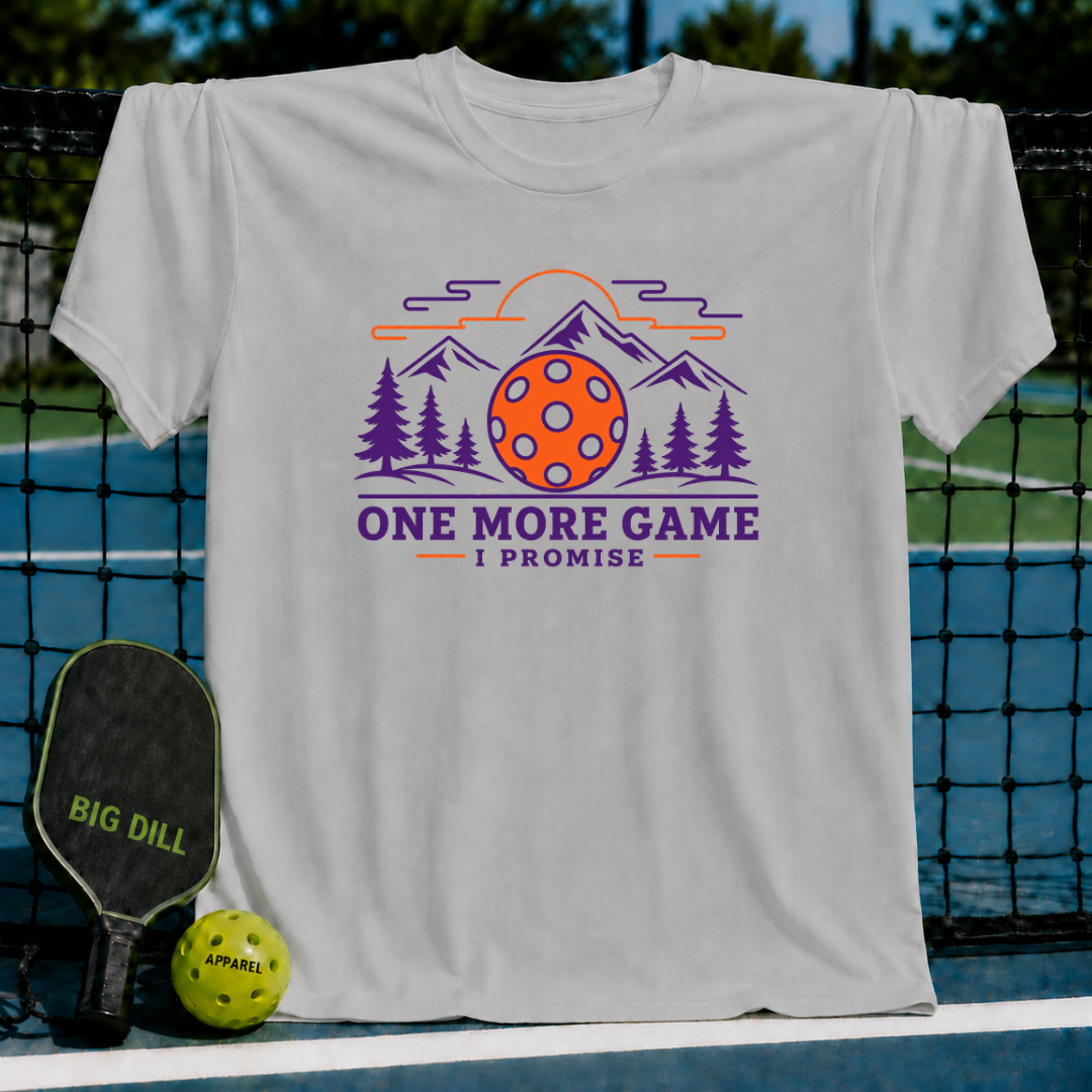 Light grey cotton t-shirt featuring a mountain, pine forest, and pickleball graphic with the text One More Game I Promise.