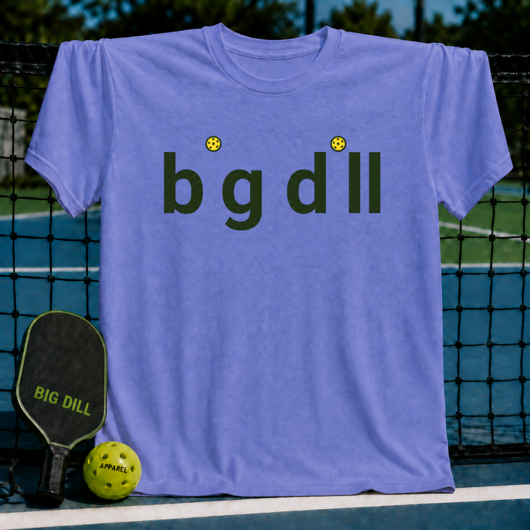 Heather blue unisex t-shirt featuring Big Dill text with yellow pickleball dots over the i's, displayed on a pickleball court.