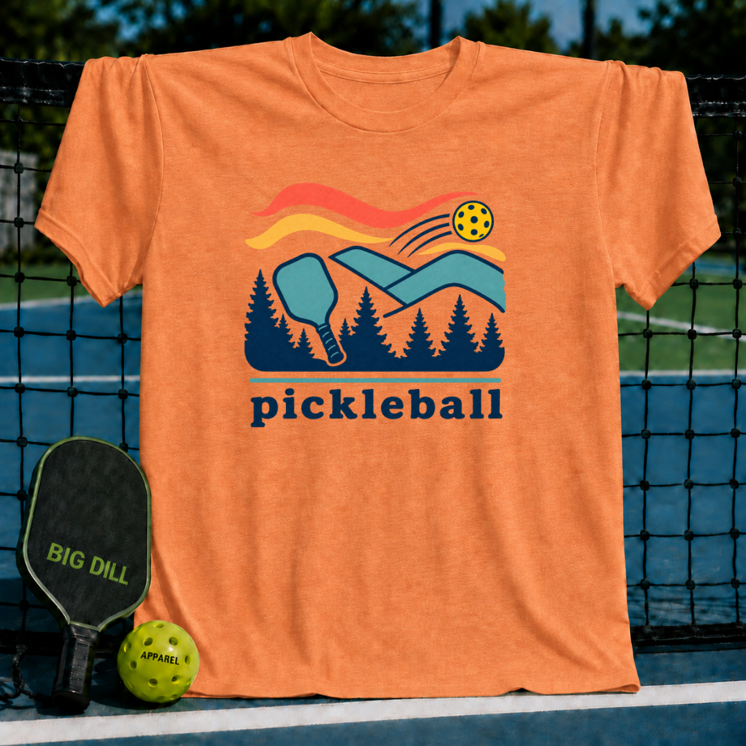 Orange crewneck t-shirt featuring a retro pickleball, paddle, and forest graphic with the word pickleball printed below.