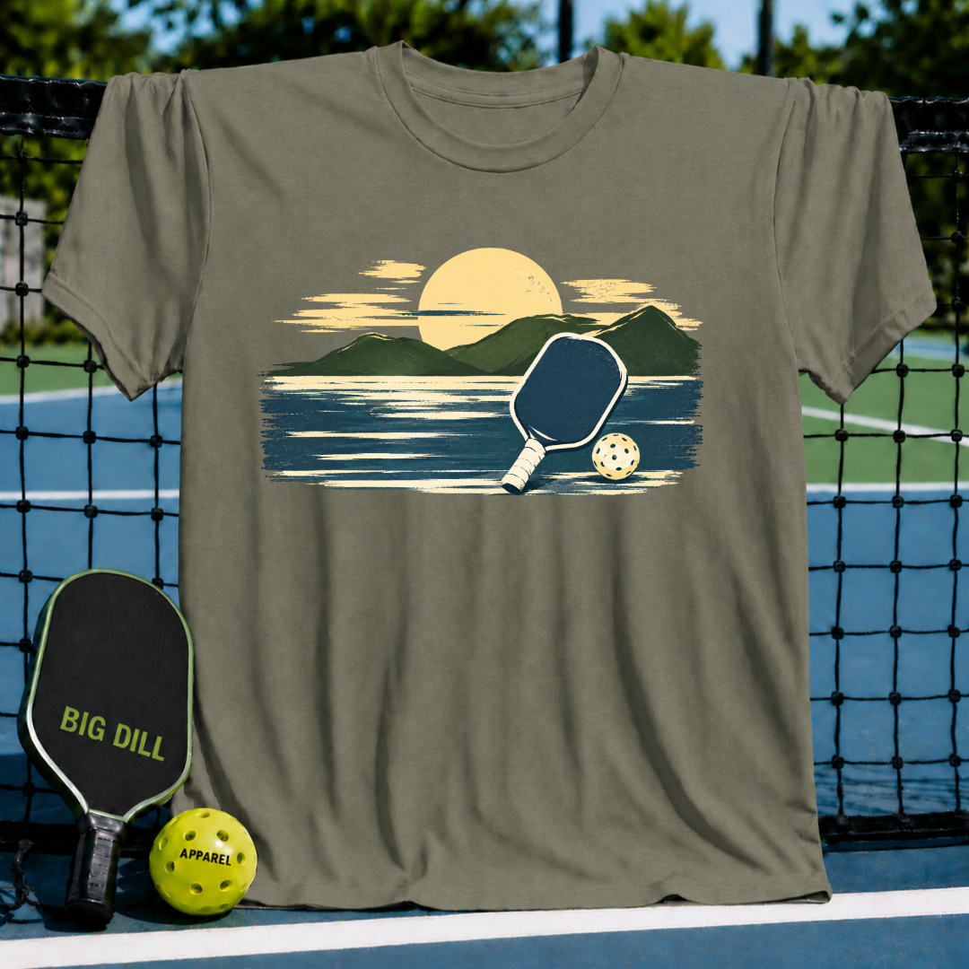 Military olive unisex t-shirt featuring a painterly mountain and pickleball graphic in golden and navy tones.