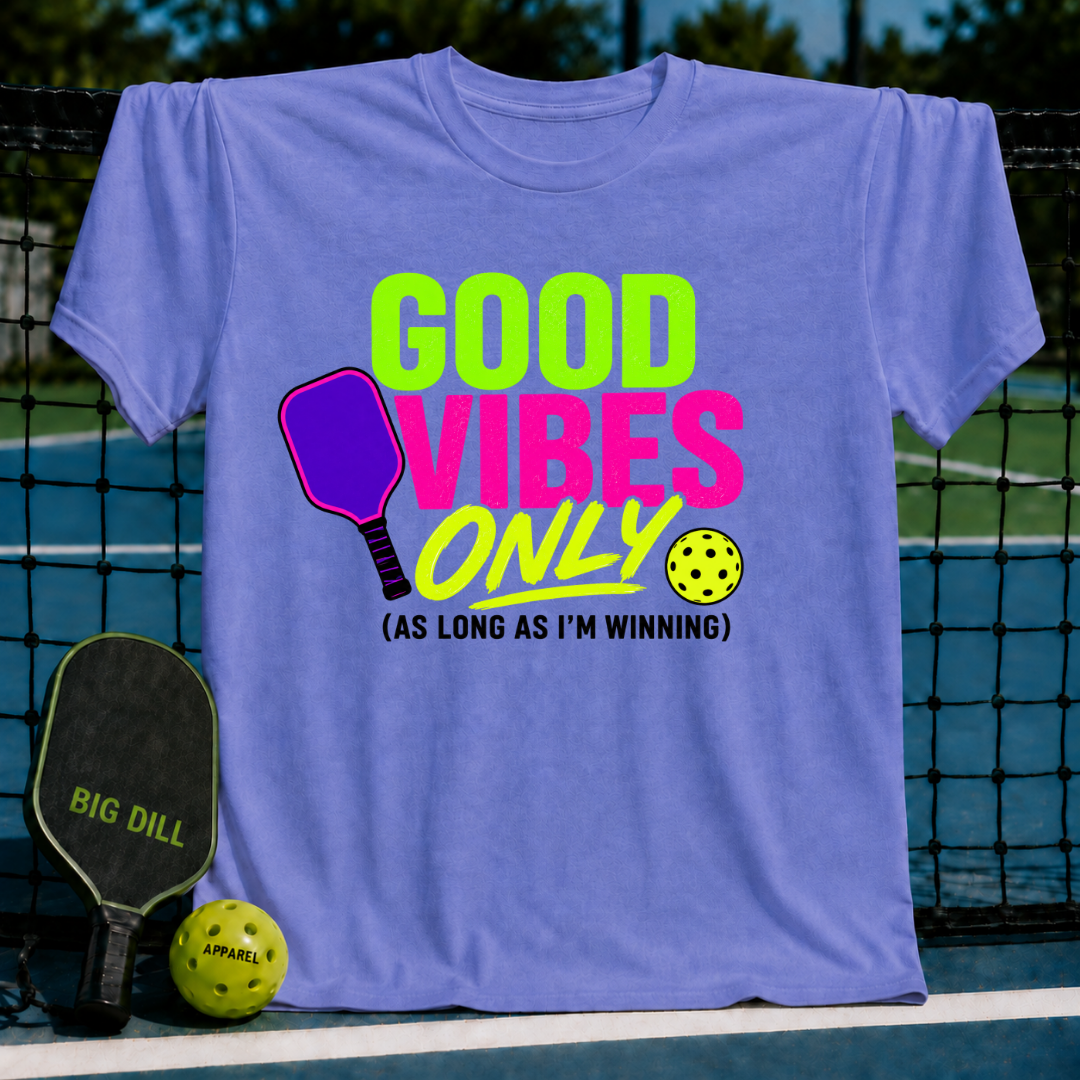 Periwinkle unisex t-shirt with neon green and pink pickleball graphic text on a tennis court background.