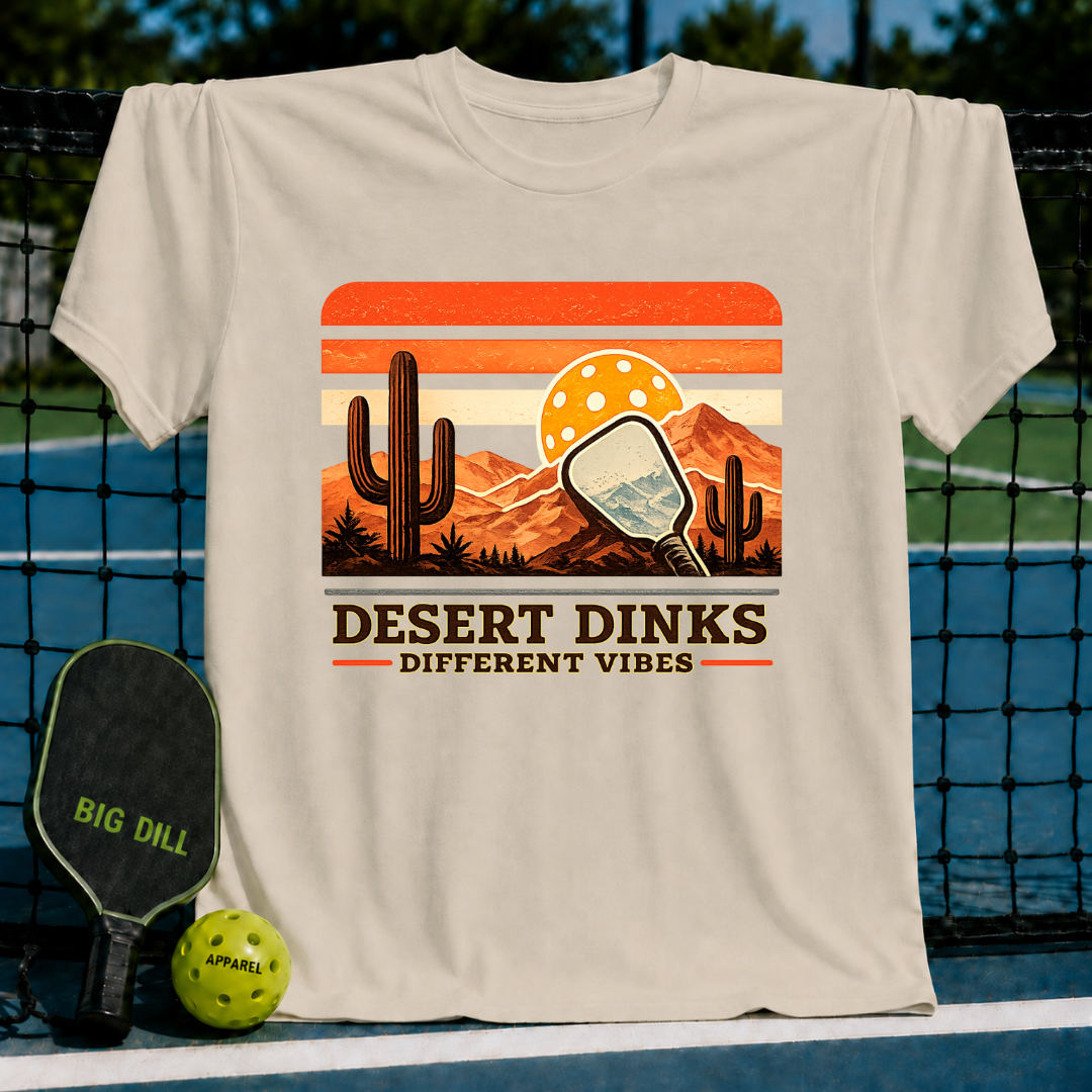 Beige crewneck t-shirt featuring a retro desert landscape graphic with a pickleball paddle, cactus, and sunset.