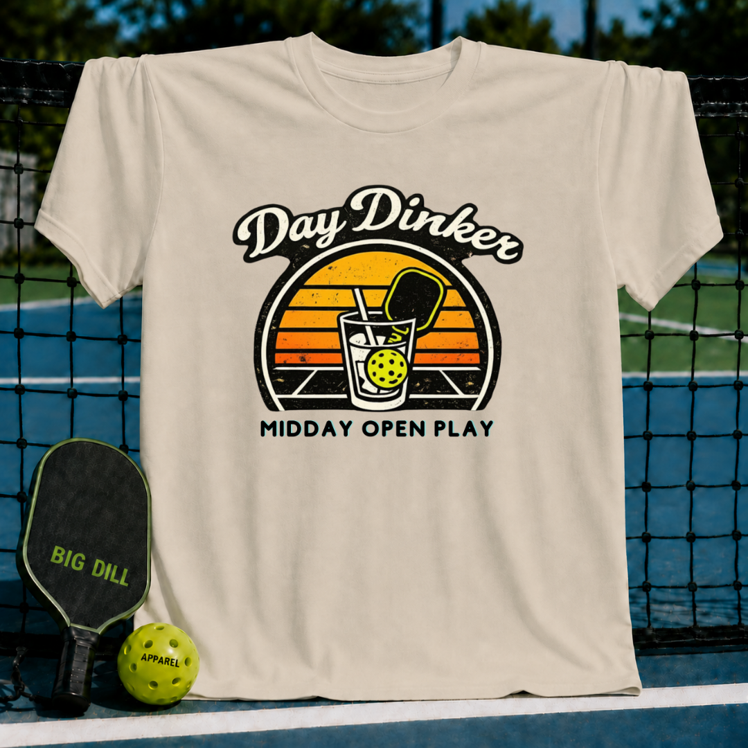 Cream-colored unisex t-shirt featuring a retro sunset graphic of a pickleball paddle and ball in a glass.