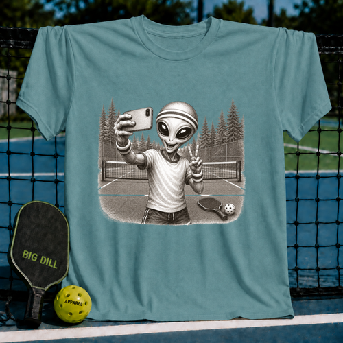 Sage green unisex t-shirt featuring a vintage-style illustration of an alien taking a selfie on a pickleball court.