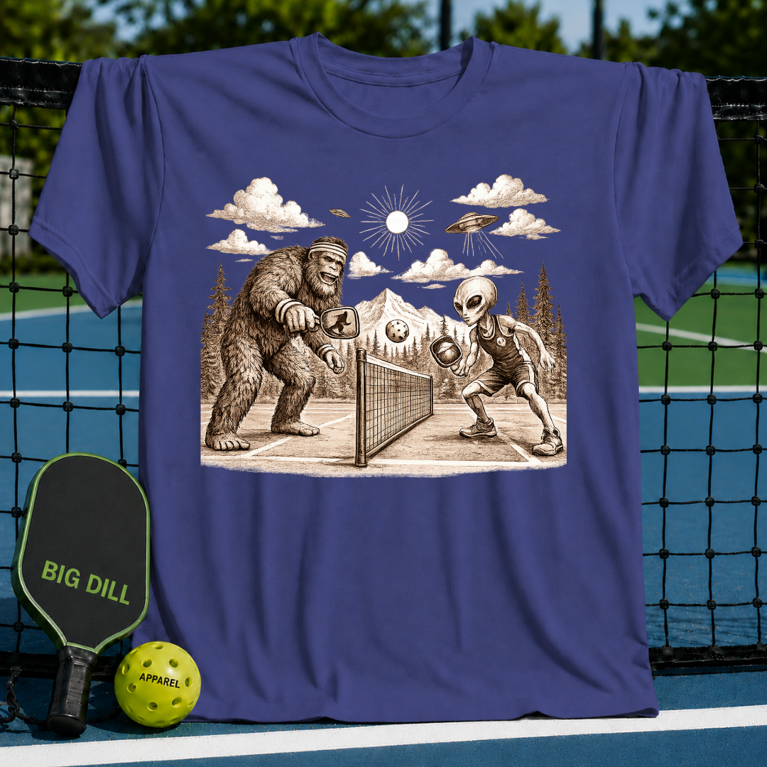 Blue unisex t-shirt featuring a vintage-style graphic of Bigfoot and an alien playing pickleball on a court.