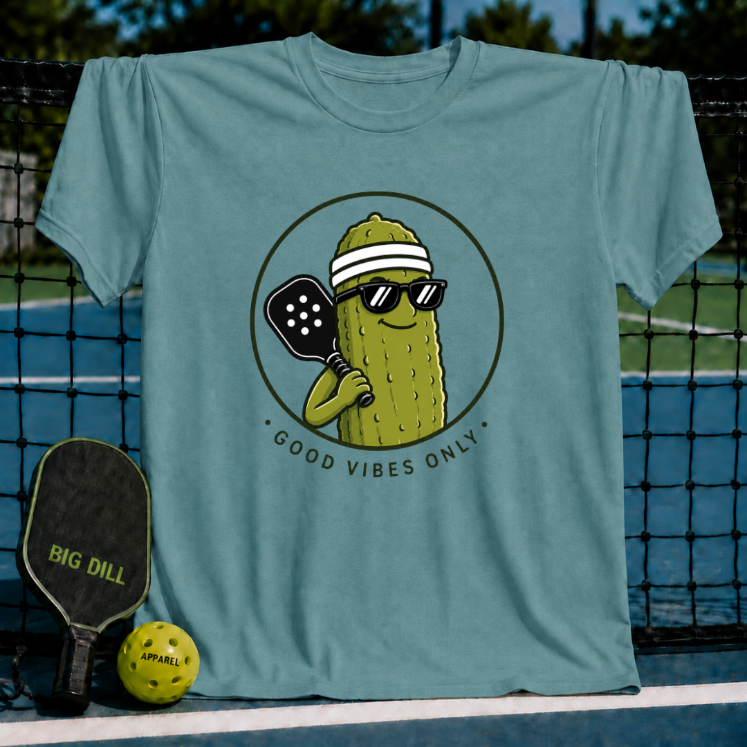 Blue-grey unisex t-shirt featuring a smiling pickle character in sunglasses and a visor holding a pickleball paddle.