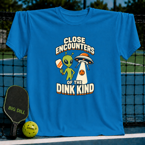 Bright blue crewneck T-shirt featuring a green alien holding a pickleball paddle next to a UFO graphic.