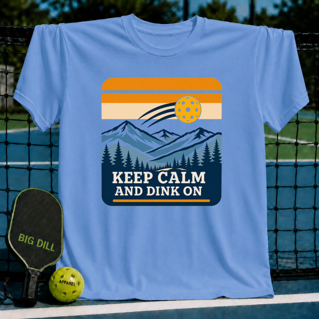 Light blue t-shirt featuring a mountain landscape graphic, a pickleball, and the text Keep Calm And Dink On.