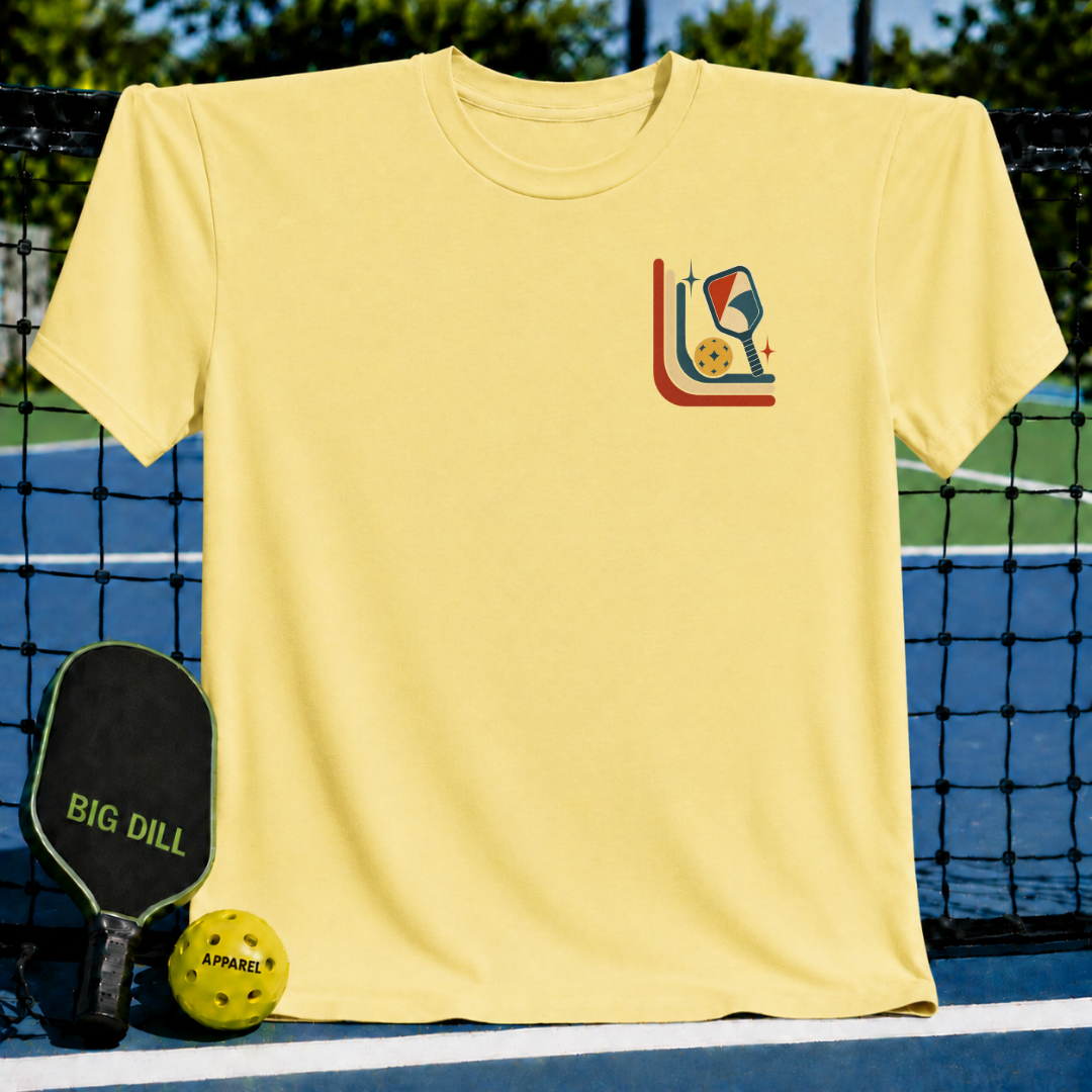 Light yellow unisex t-shirt featuring a mid-century retro pickleball graphic on a pickleball court background.