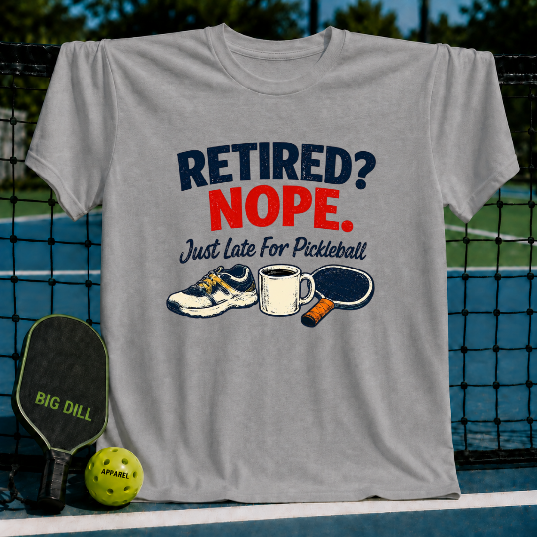 Grey crewneck t-shirt featuring a Retired? Nope. Just Late For Pickleball graphic with a sneaker, coffee mug, and paddle.