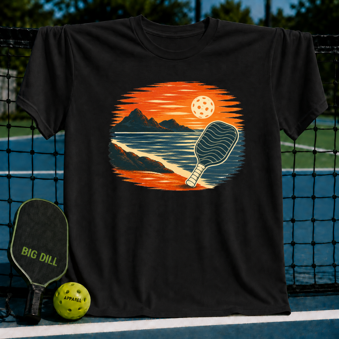 Black unisex t-shirt featuring a vintage oval sunset illustration of a pickleball paddle on a shoreline.