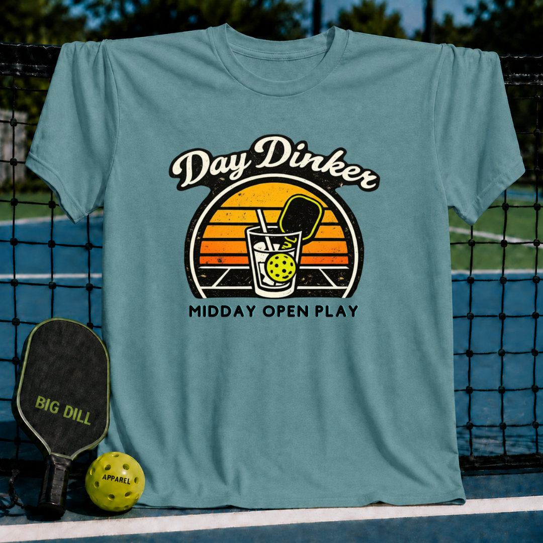 Periwinkle blue unisex t-shirt featuring a retro sunset graphic of a pickleball paddle and ball in a glass.