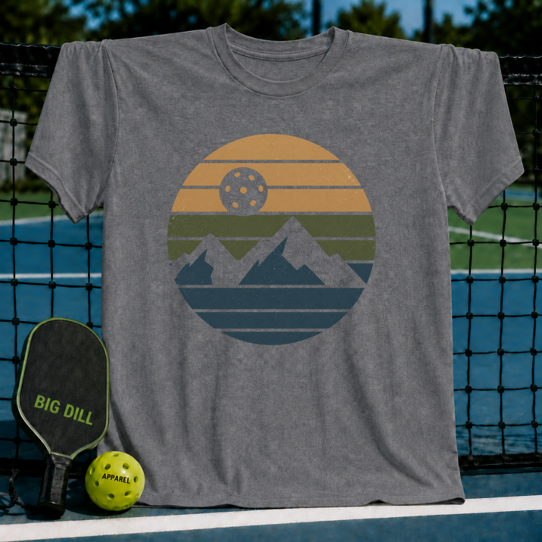 Grey unisex t-shirt featuring a retro circular graphic of mountains and a pickleball sun on a court background.
