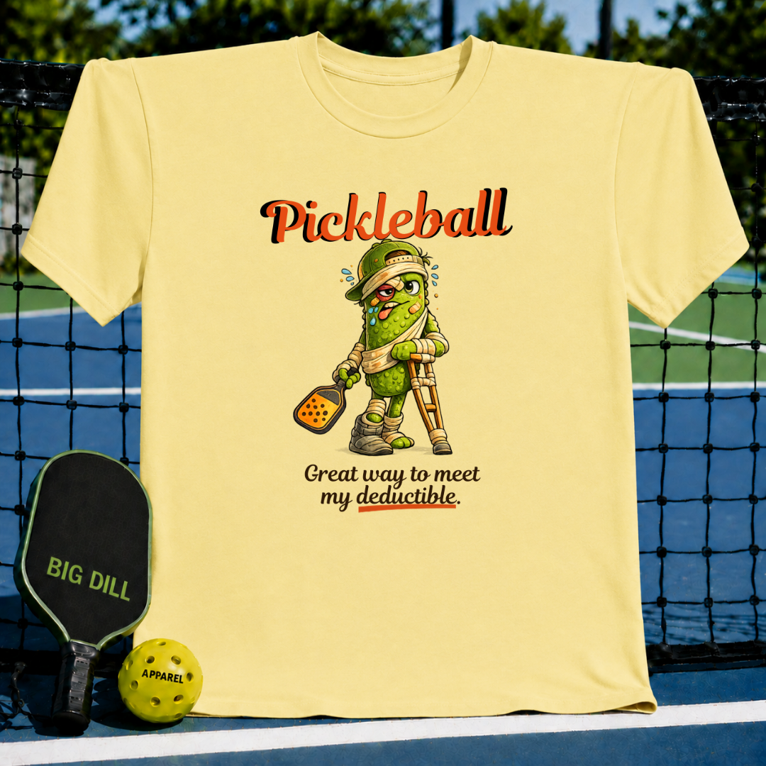 Light yellow unisex t-shirt featuring a cartoon pickle on crutches with a paddle and the text Pickleball: Great way to meet my deductible.