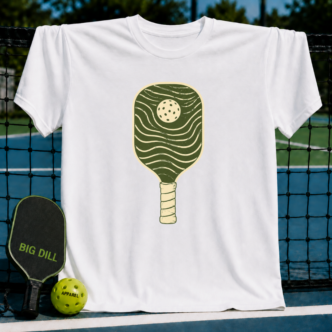 Cream unisex t-shirt featuring a minimalist forest green pickleball paddle graphic with organic wave patterns.